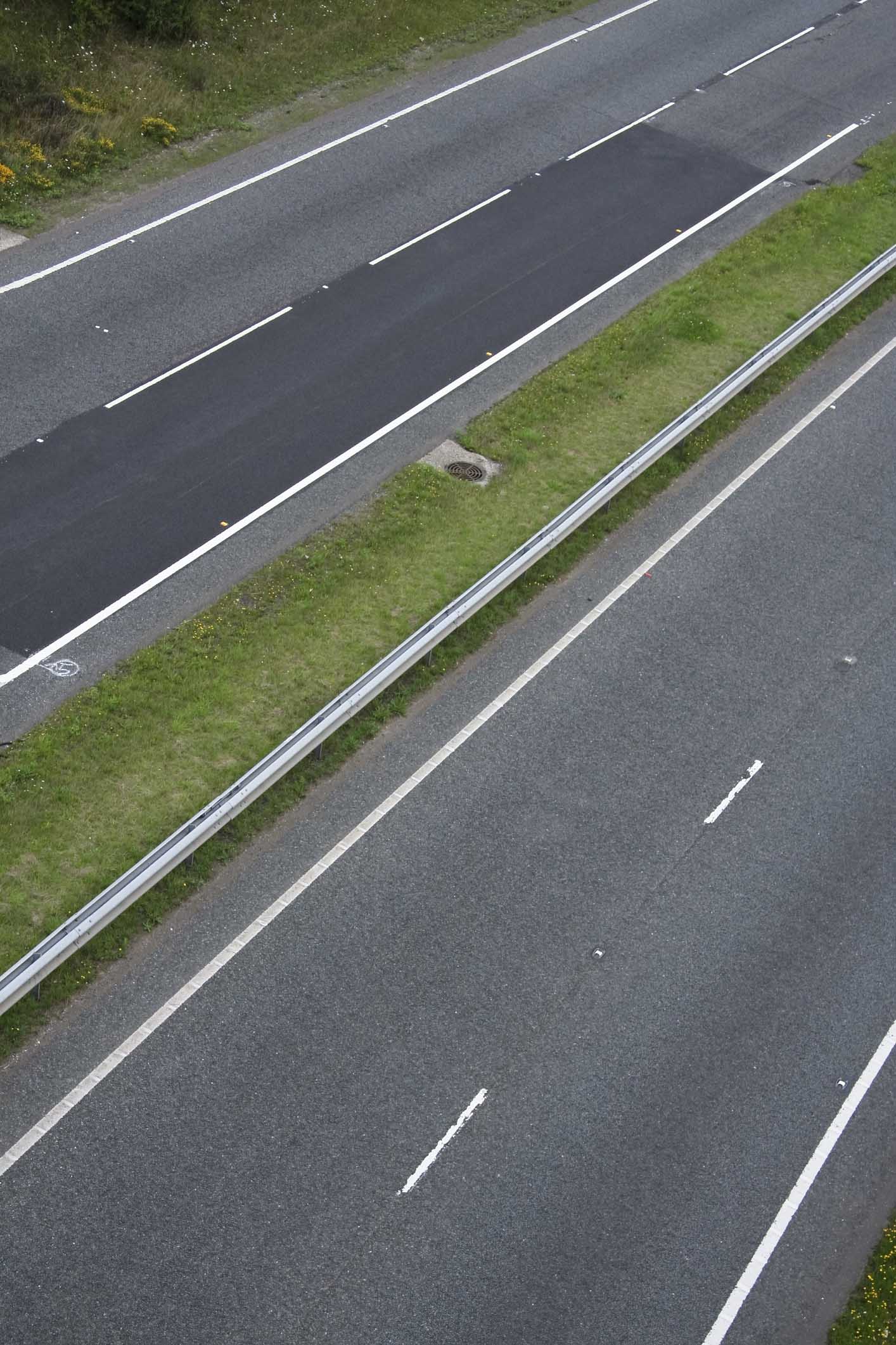 Dual carriageway two lane blacktop road. Detail of two lane motorway road shot from overhead in the uk